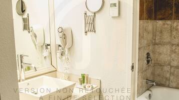 Une salle de bain avec un lavabo blanc, un miroir, un sèche-cheveux et une douche.