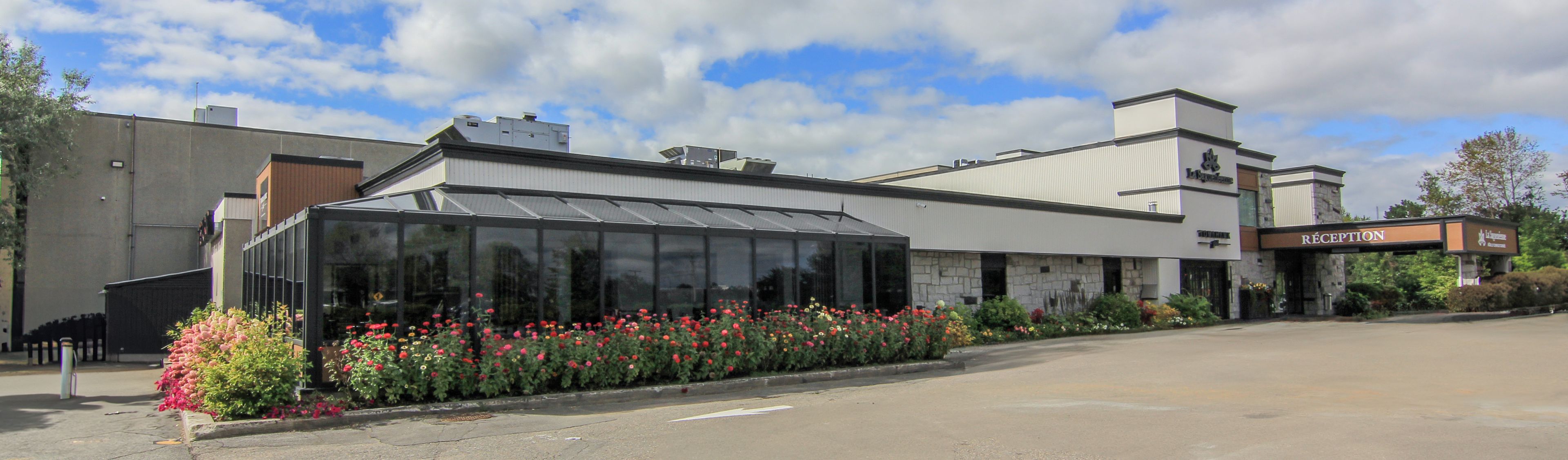 A modern building with a reception area, large windows, and a parking lot.