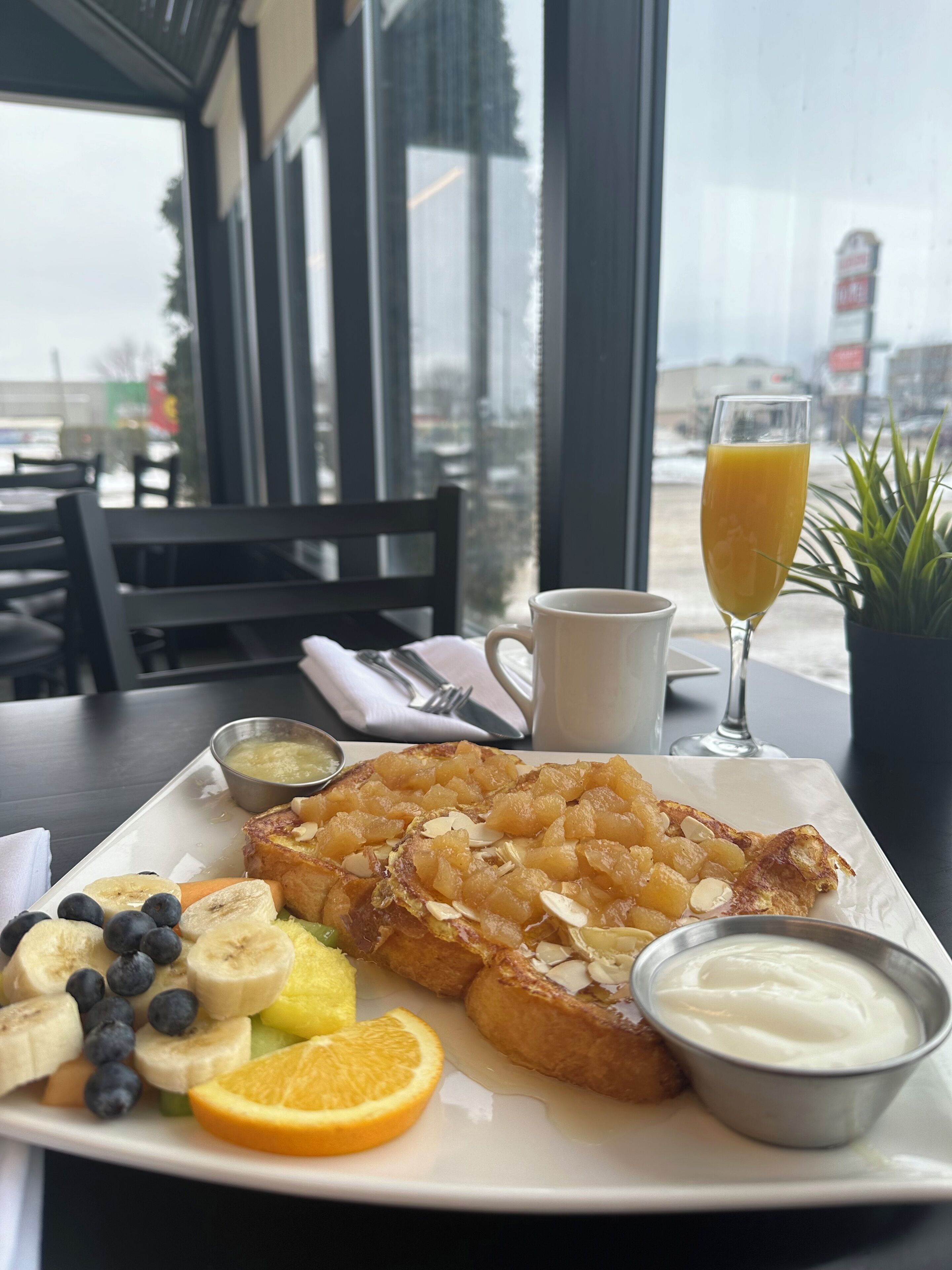 A breakfast plate with toast, fruit, and a glass of orange juice.