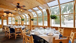 A restaurant with wooden interiors, large windows, and a view of a snowy mountain. - Alta Peruvian Lodge (Sandy)