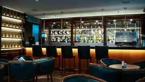 A bar area with multiple seating options, including bar stools and round tables, and a well-stocked liquor shelf. - Amérian Buenos Aires (Buenos Aires)