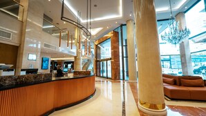 A modern lobby with a reception desk, large columns, a chandelier, and a seating area. - Amérian Buenos Aires (Buenos Aires)