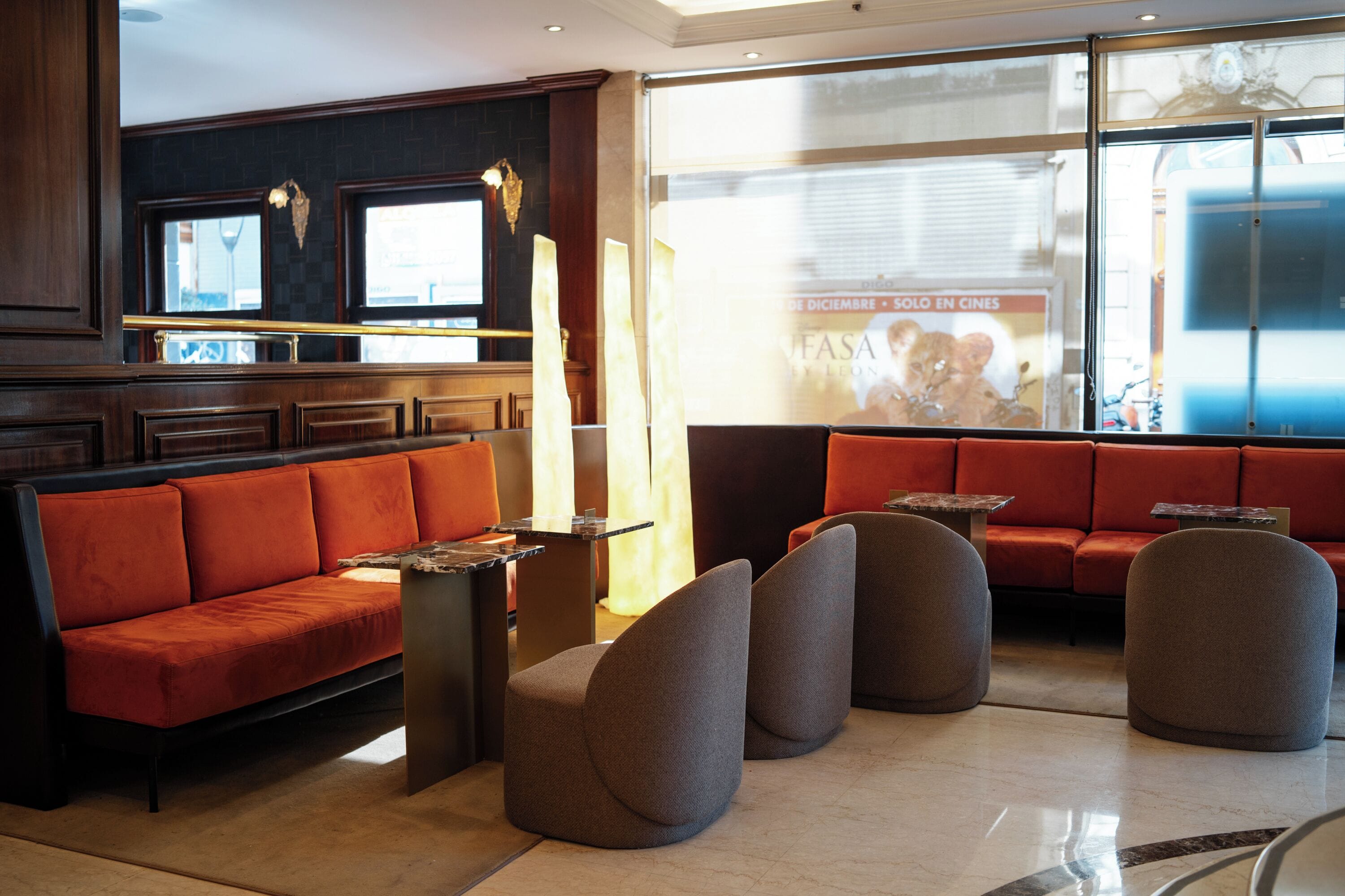 A modern lobby with a red sofa, a bar area, and a seating area with round chairs.