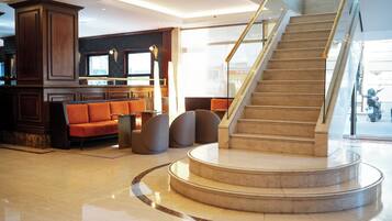 A lobby with a marble staircase, seating area, and a reception desk.