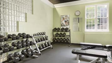 Una sala de gimnàstica amb estands de peses, halteres, kettlebells i equip d'exercici.