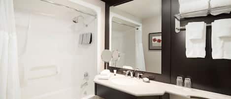 Un baño moderno con bañera, lavamanos, un espejo grande y un perchero para toallas.