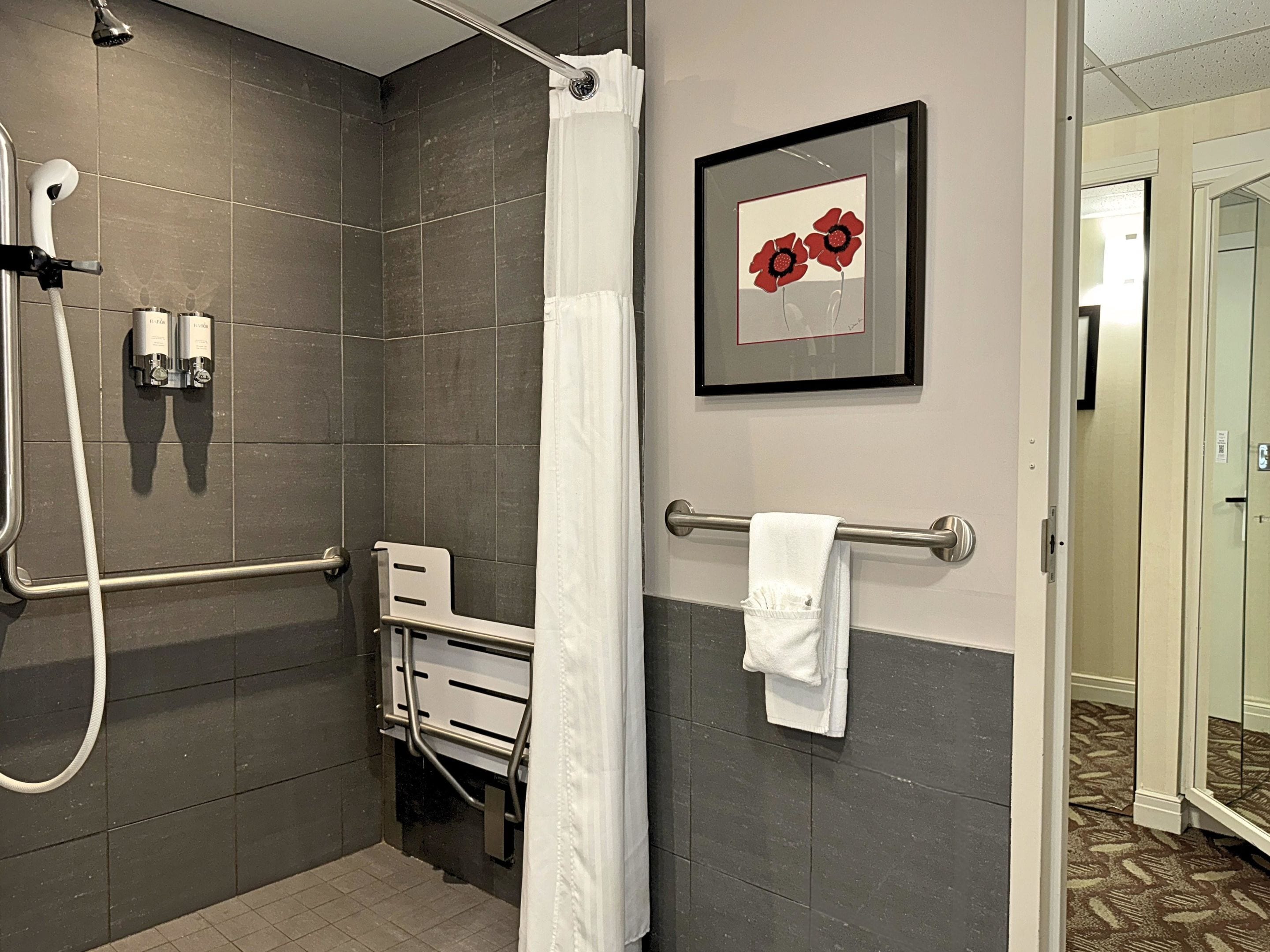 A shower area with a glass door, a towel rack, and a framed picture on the wall.