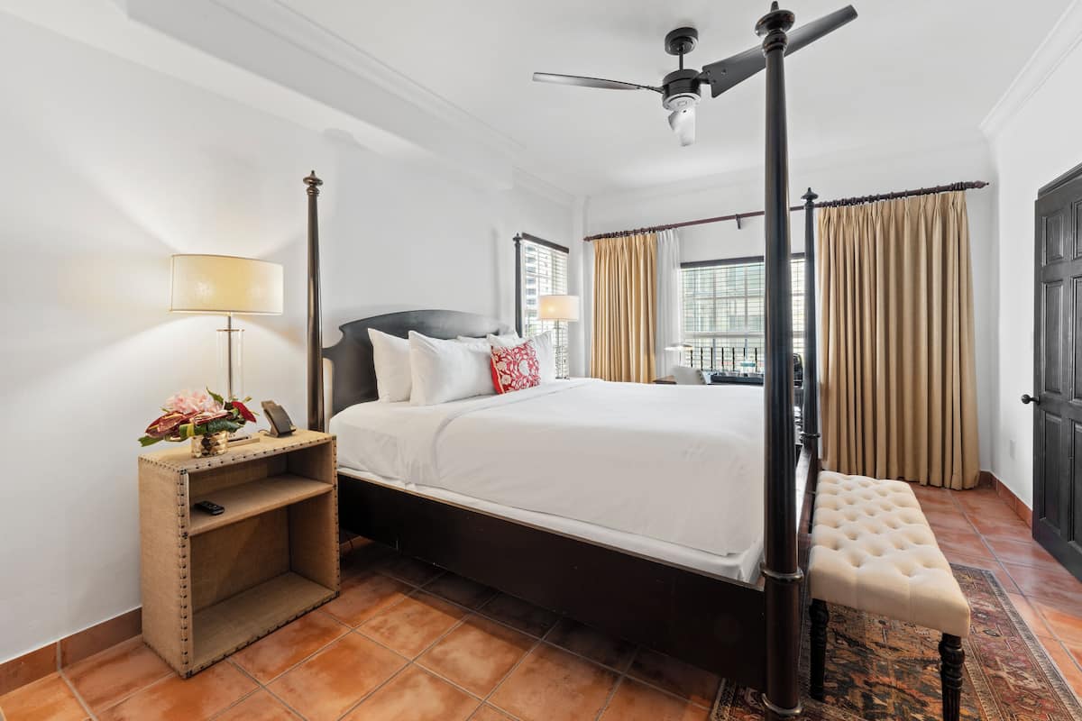 A neatly arranged bedroom with a bed, bedside table, lamp, and a bench.