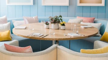 A dining area with a round table, chairs, and framed artwork on the wall.