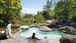 A person relaxing in a stone pool surrounded by large rocks and greenery. - Skamania Lodge (Stevenson)