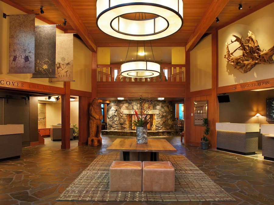 A lobby with a stone fireplace, wooden reception desk, and a large chandelier.