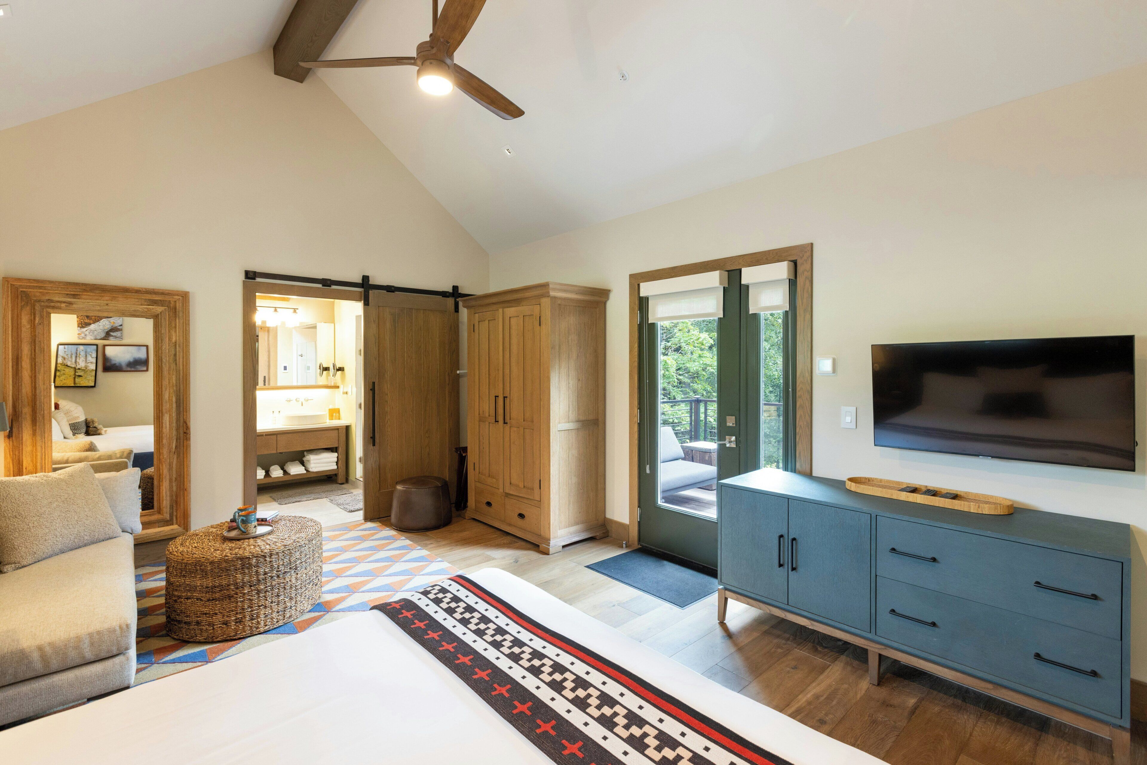 A bedroom with a bed, a TV, a wardrobe, and a ceiling fan.