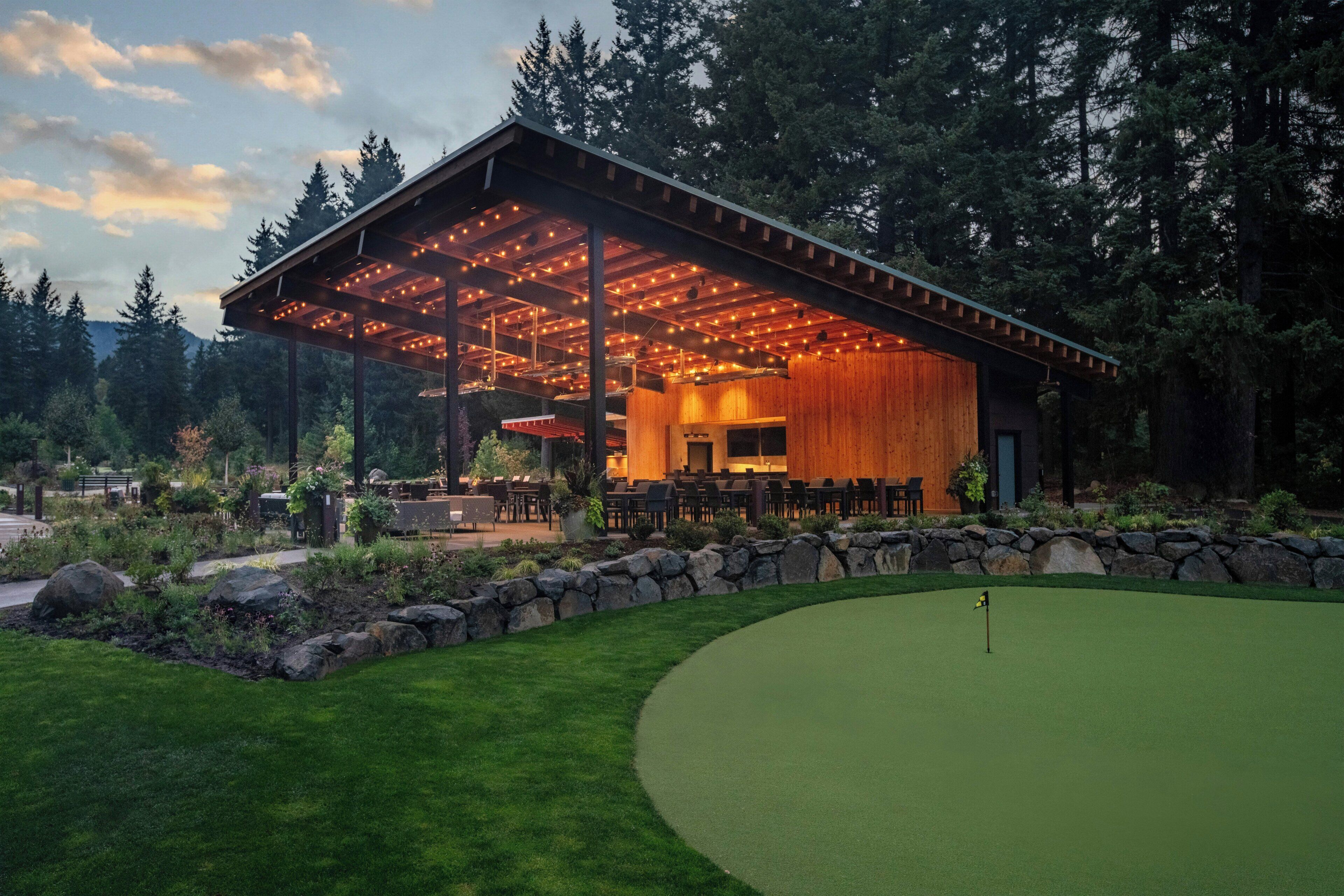 A building with a covered patio area, surrounded by a well-maintained lawn and a golf course.