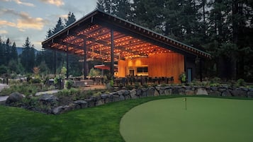 A building with a covered patio area, surrounded by a well-maintained lawn and a golf course.
