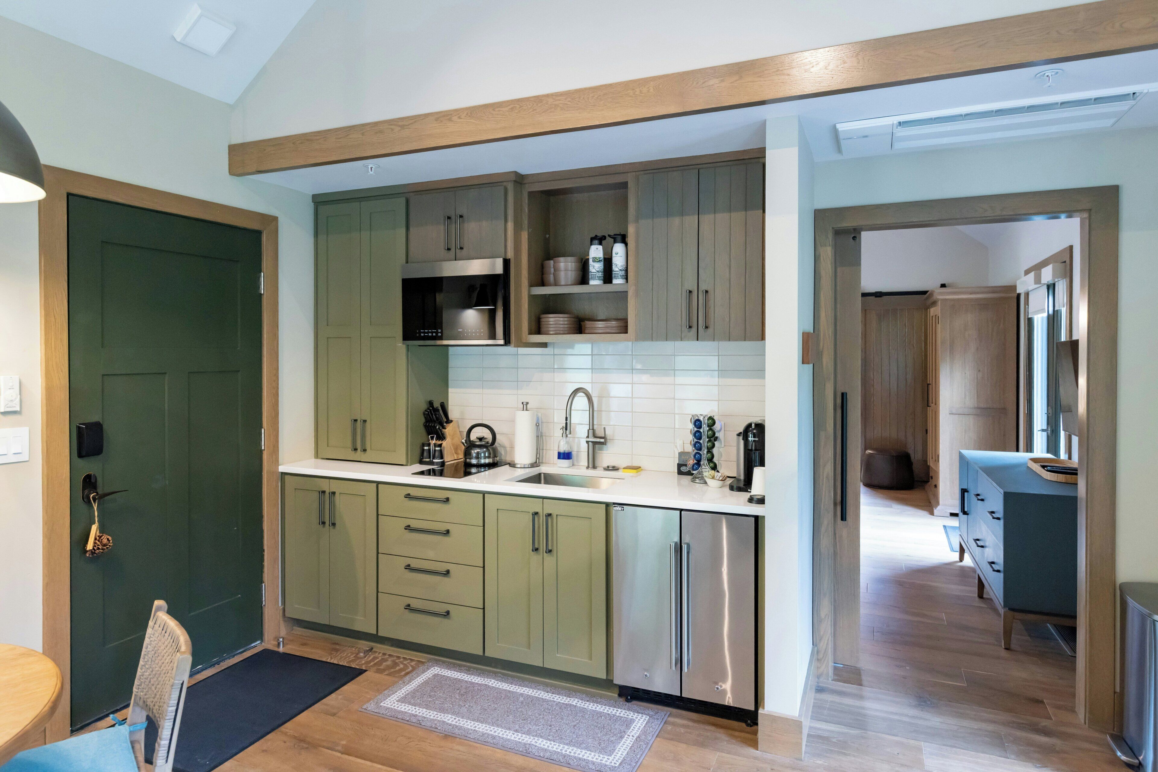 Una cocina moderna con armarios verdes, electrodomésticos de acero inoxidable y techo de madera.