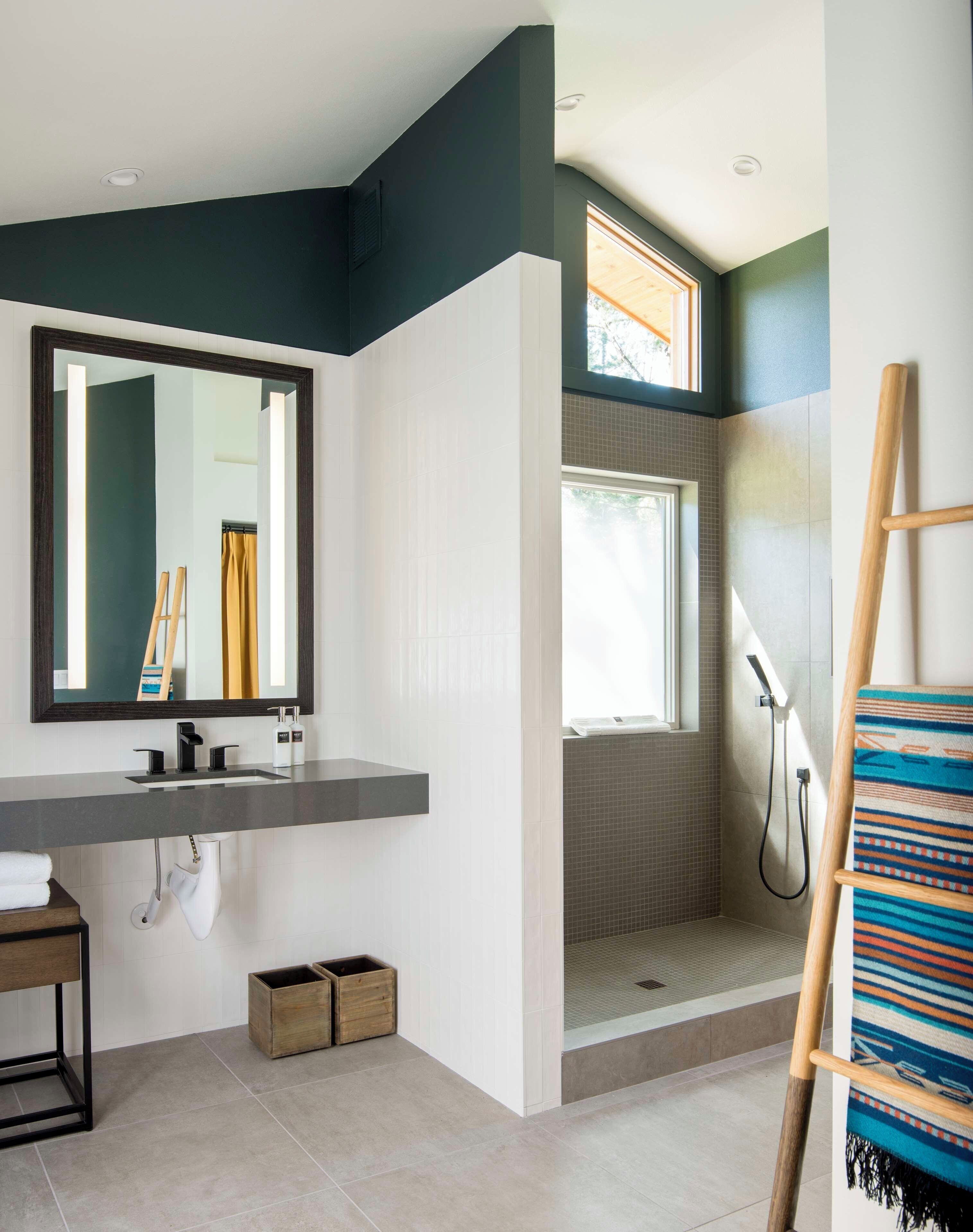 Un baño moderno con un espejo grande, zona de ducha y una escalera de madera.