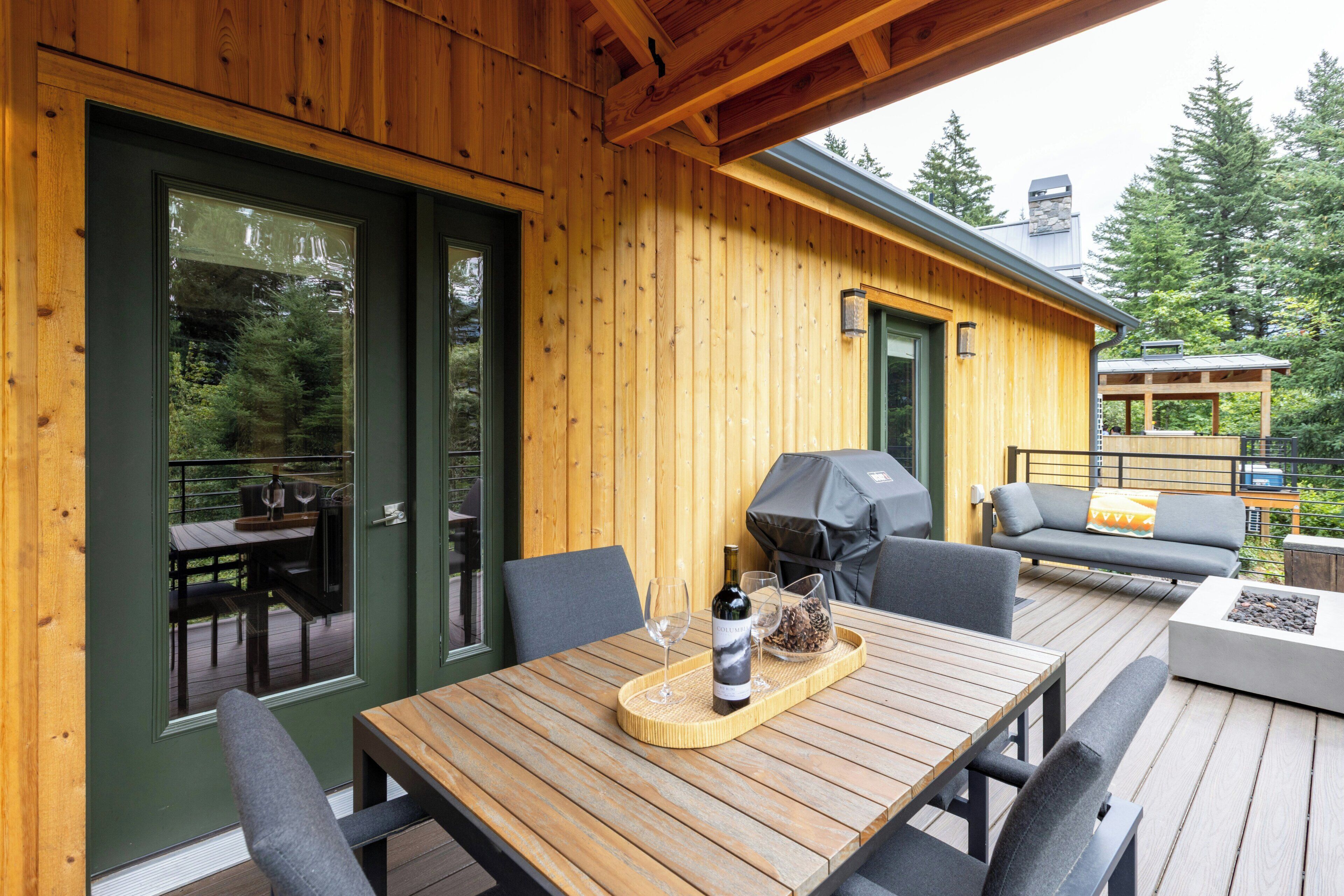 A wooden deck with outdoor furniture, including a table and chairs, and a barbecue grill.