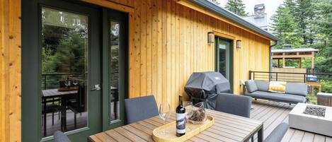 A wooden deck with outdoor furniture, including a table and chairs, and a barbecue grill.