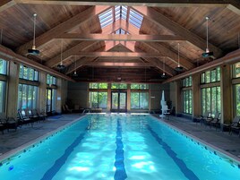 A large indoor swimming pool with wooden beams and large windows.