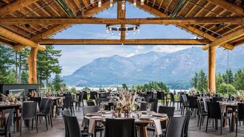 An outdoor dining area with tables and chairs, a wooden ceiling, and a mountain view.