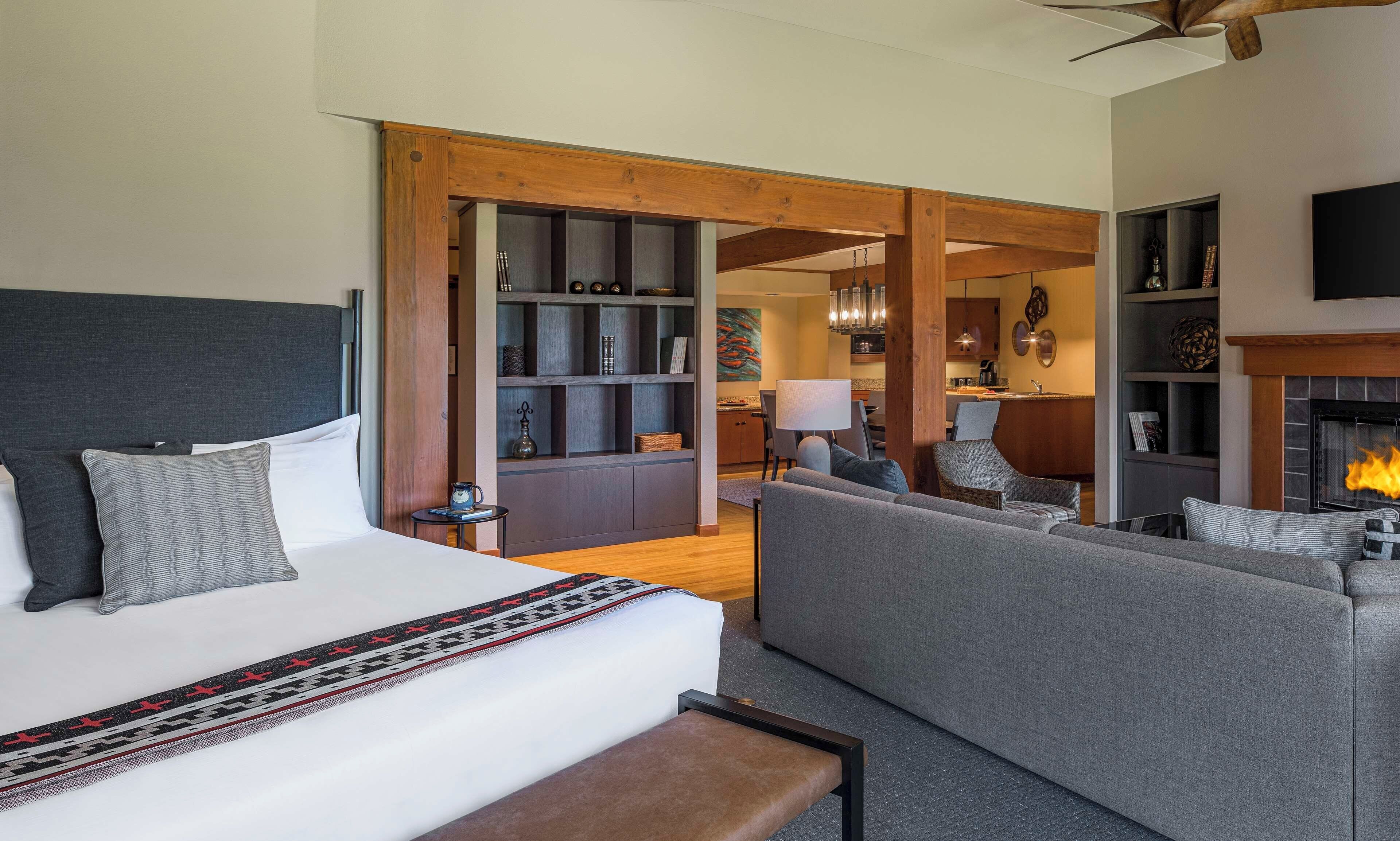 Ett hotellrum med en säng, en soffa, en öppen spis och en matplats.