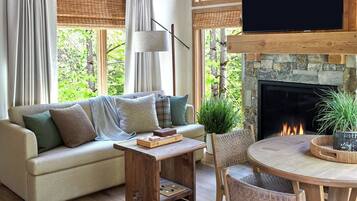 Un salon chaleureux avec une cheminée, un canapé, une table basse et un téléviseur fixé au mur.