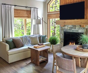 Una sala de estar acogedora con chimenea, un sofá, una mesa de centro y un televisor montado en la pared.