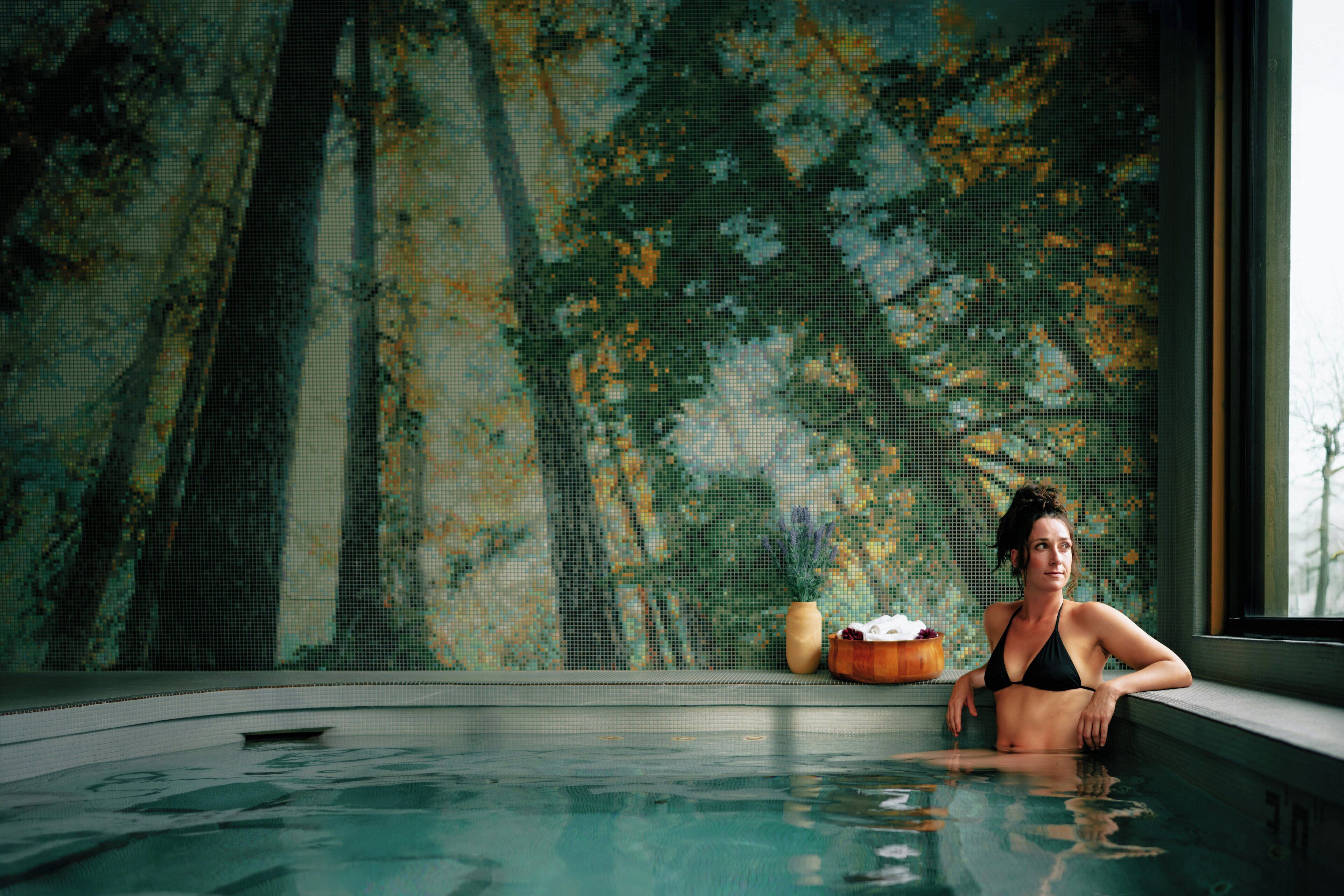 A person in a hot tub with a mosaic wall in the background.