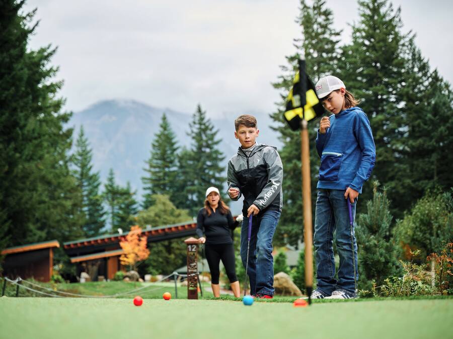 A golf course with a wooden structure, a flag, and a mountain in the background.