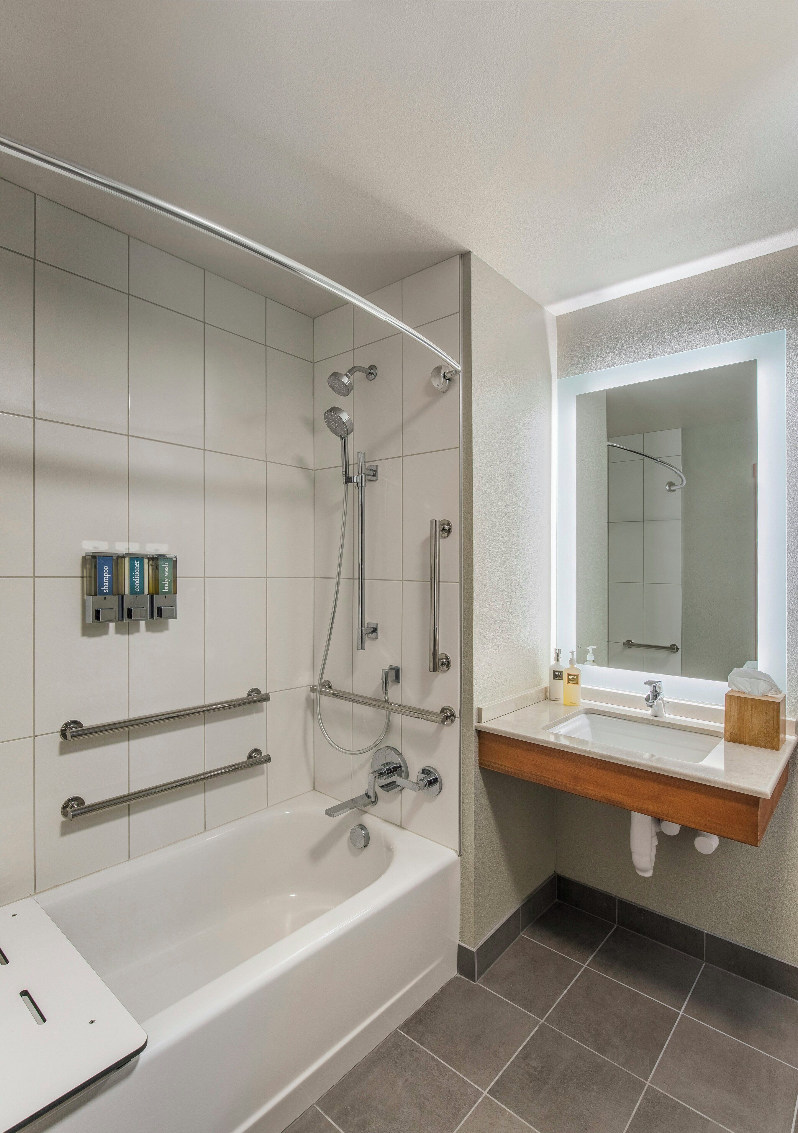 Een moderne badkamer met een bad, een douche met handdouche, een wastafel met spiegel en een handdoekrek.