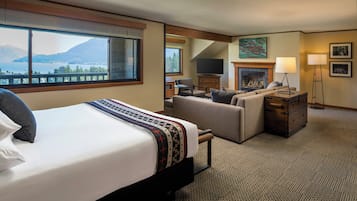 Een hotelkamer met een bed, een bank, een open haard, een televisie en uitzicht op bergen.