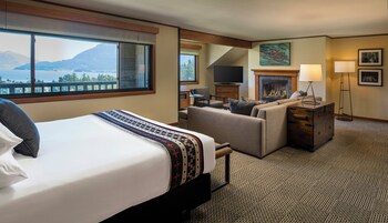 Habitación de hotel con cama, sofá, chimenea, televisor y vistas a las montañas.