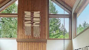 A spacious living area with a fireplace, wooden ceiling, large windows, and a dining table set for four. - Skamania Lodge (Stevenson)