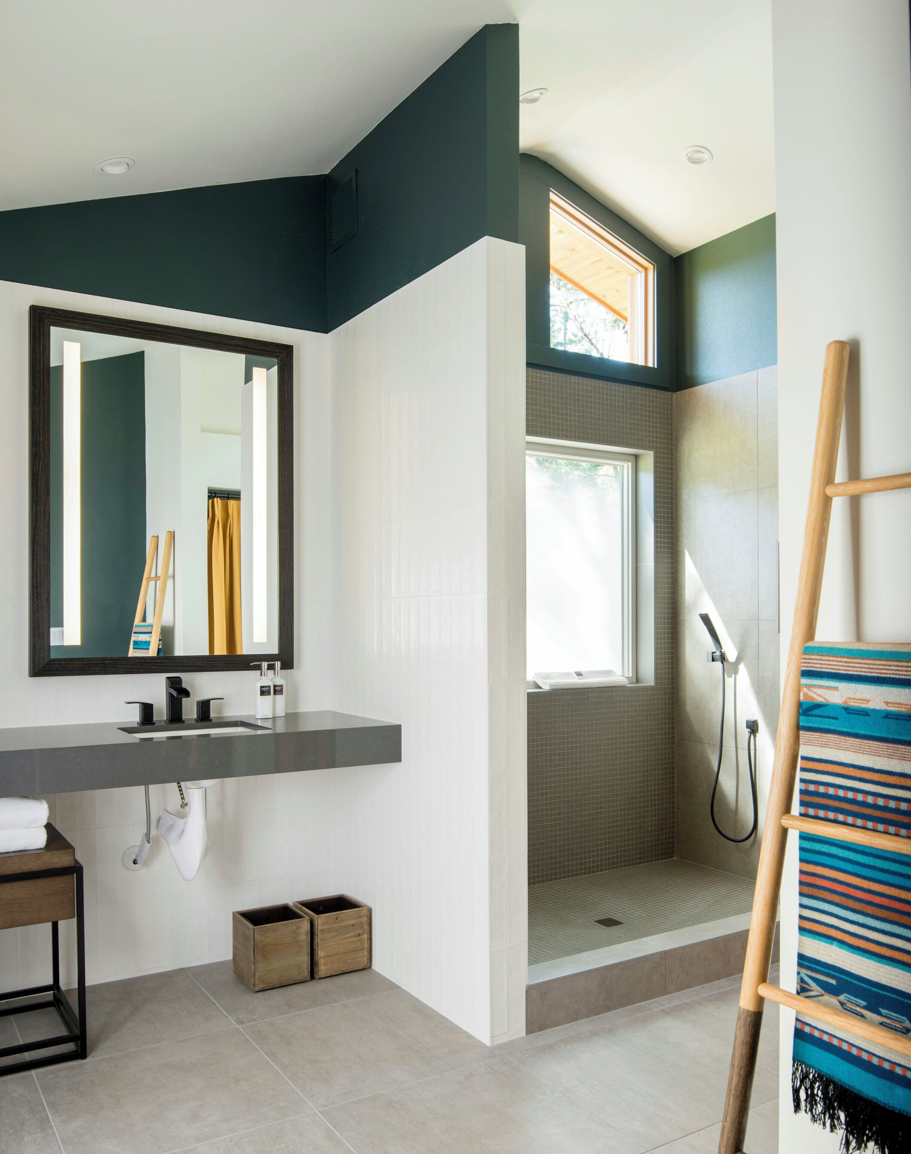 Un baño moderno con un espejo grande, una ducha y una escalera de madera.