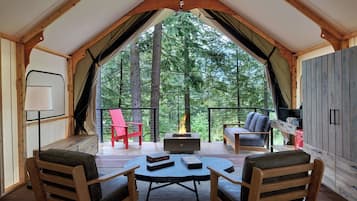A cozy interior with a wooden ceiling, a fire pit, and a view of a forest.