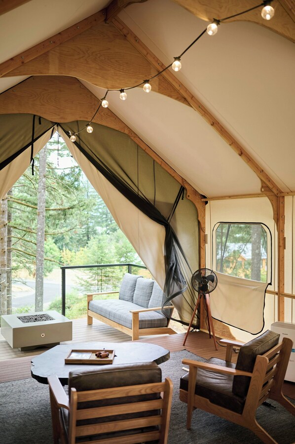 A tent with a wooden interior, a sofa, a table, and a fan.