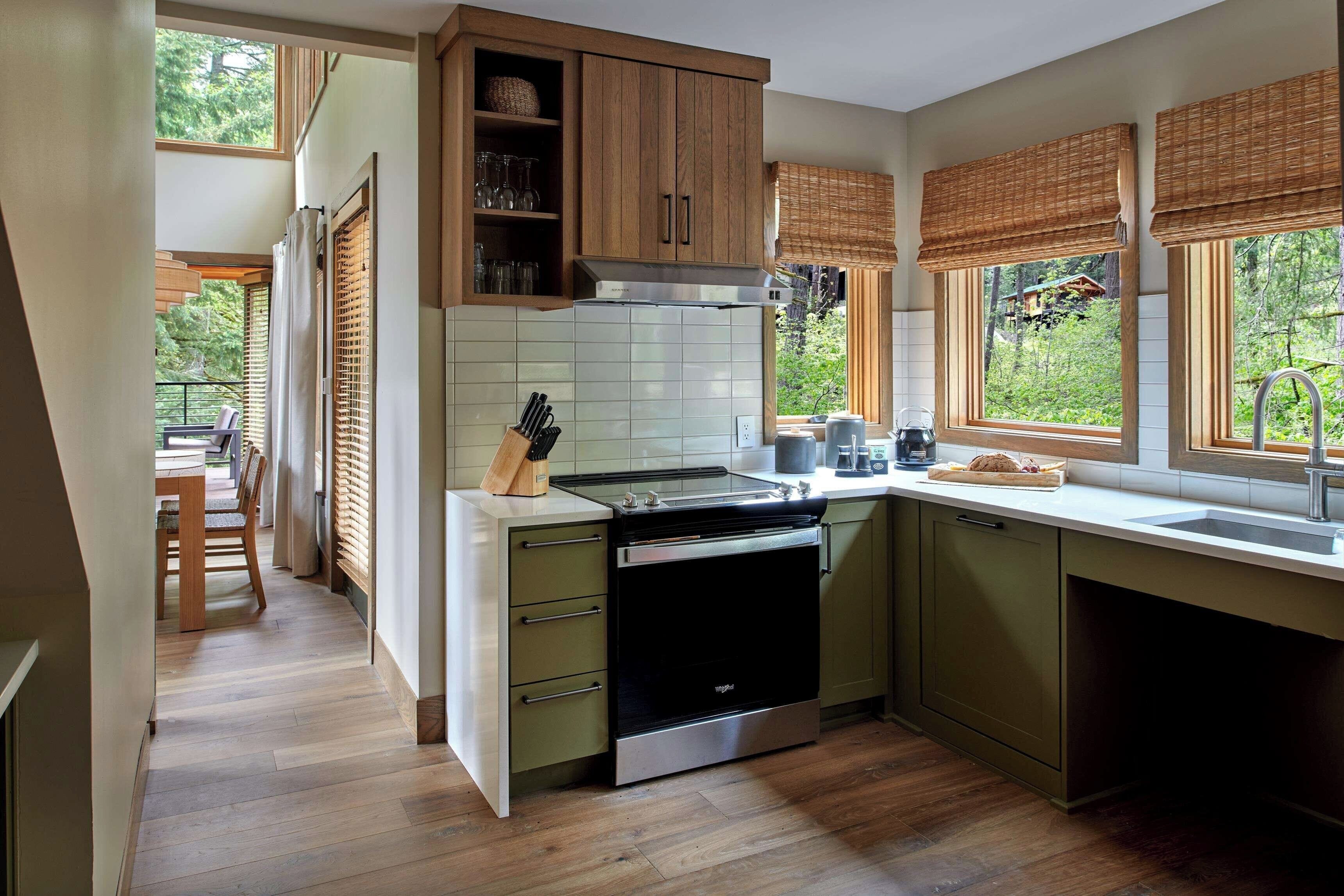 Een moderne keuken met houten kastjes, een inbouwoven en een raam met uitzicht op de omgeving.