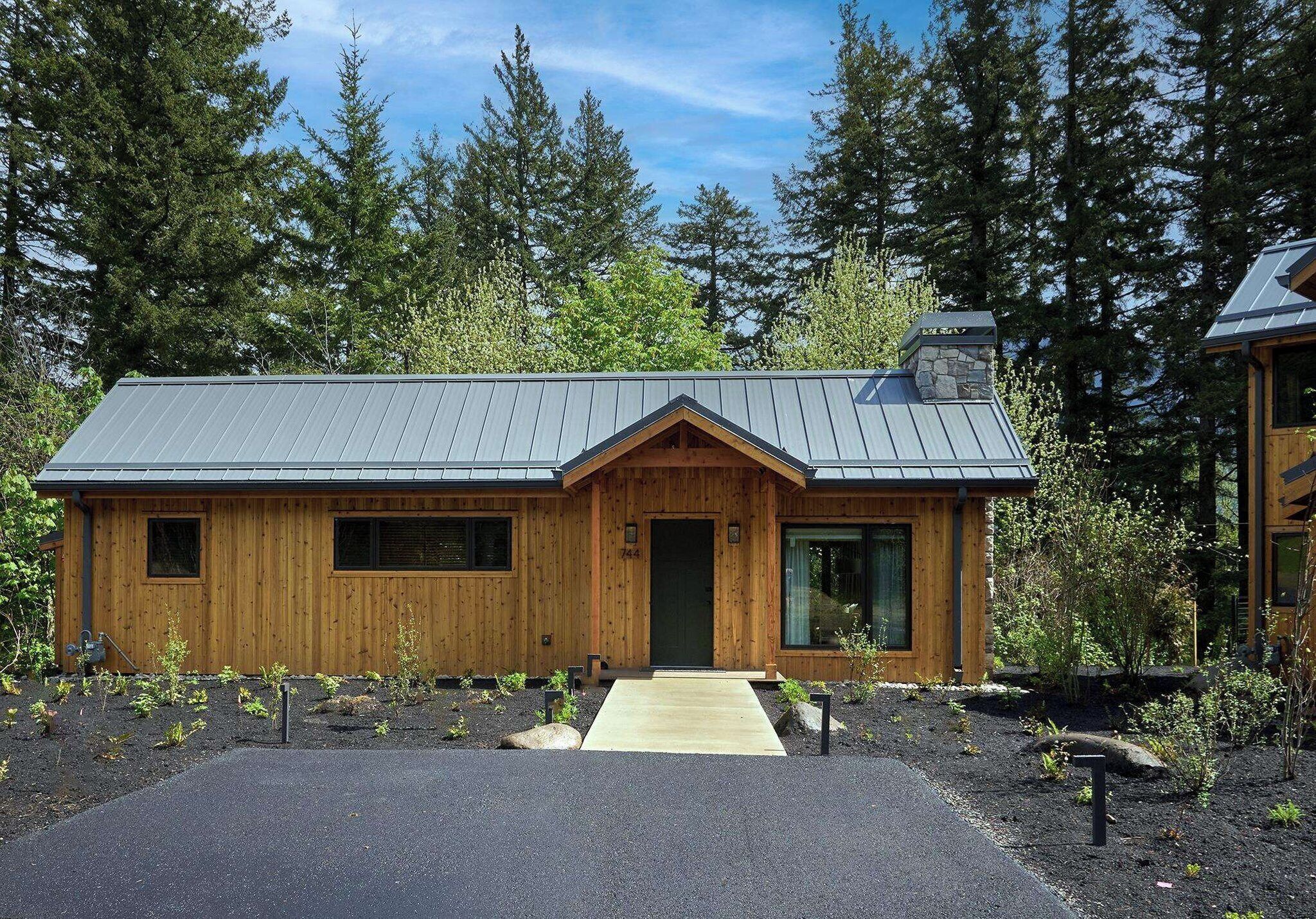 A wooden cabin with a metal roof, a front door, and a small porch.