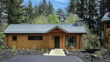 A wooden cabin with a metal roof, a front door, and a small porch.