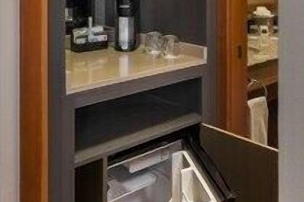 A compact bathroom with a dark wood vanity, a coffee maker, and a mirror.
