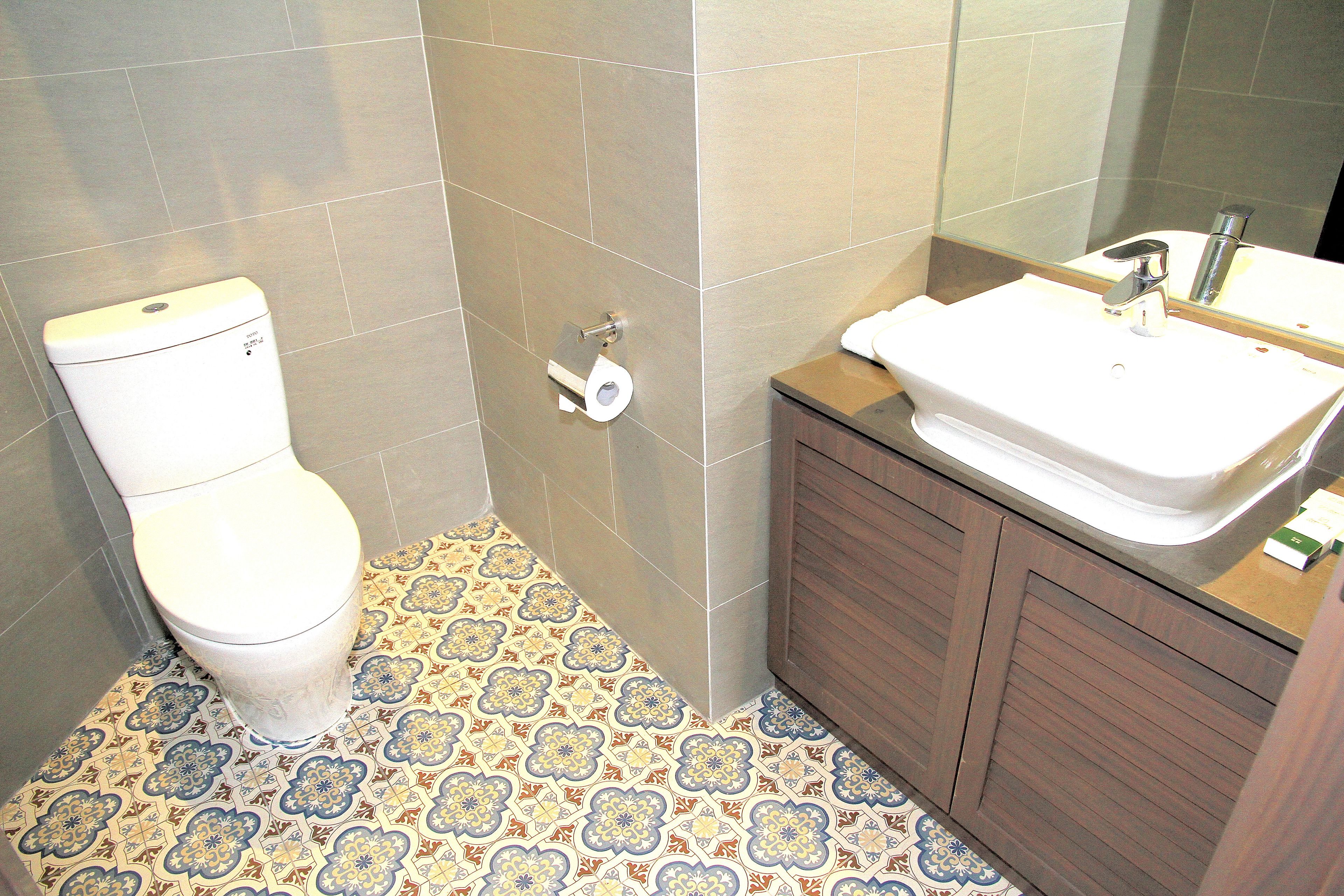 A bathroom with a toilet, a sink, and patterned floor tiles.
