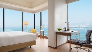 Una camera d'albergo con un letto grande, una scrivania, una sedia e vista sulla città e sul mare.