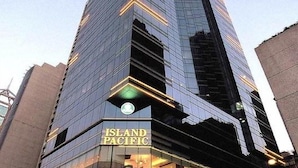 Un hotel moderno e imponente con facciata in vetro e insegna illuminata che riporta la scritta "Island Pacific Hotel".
