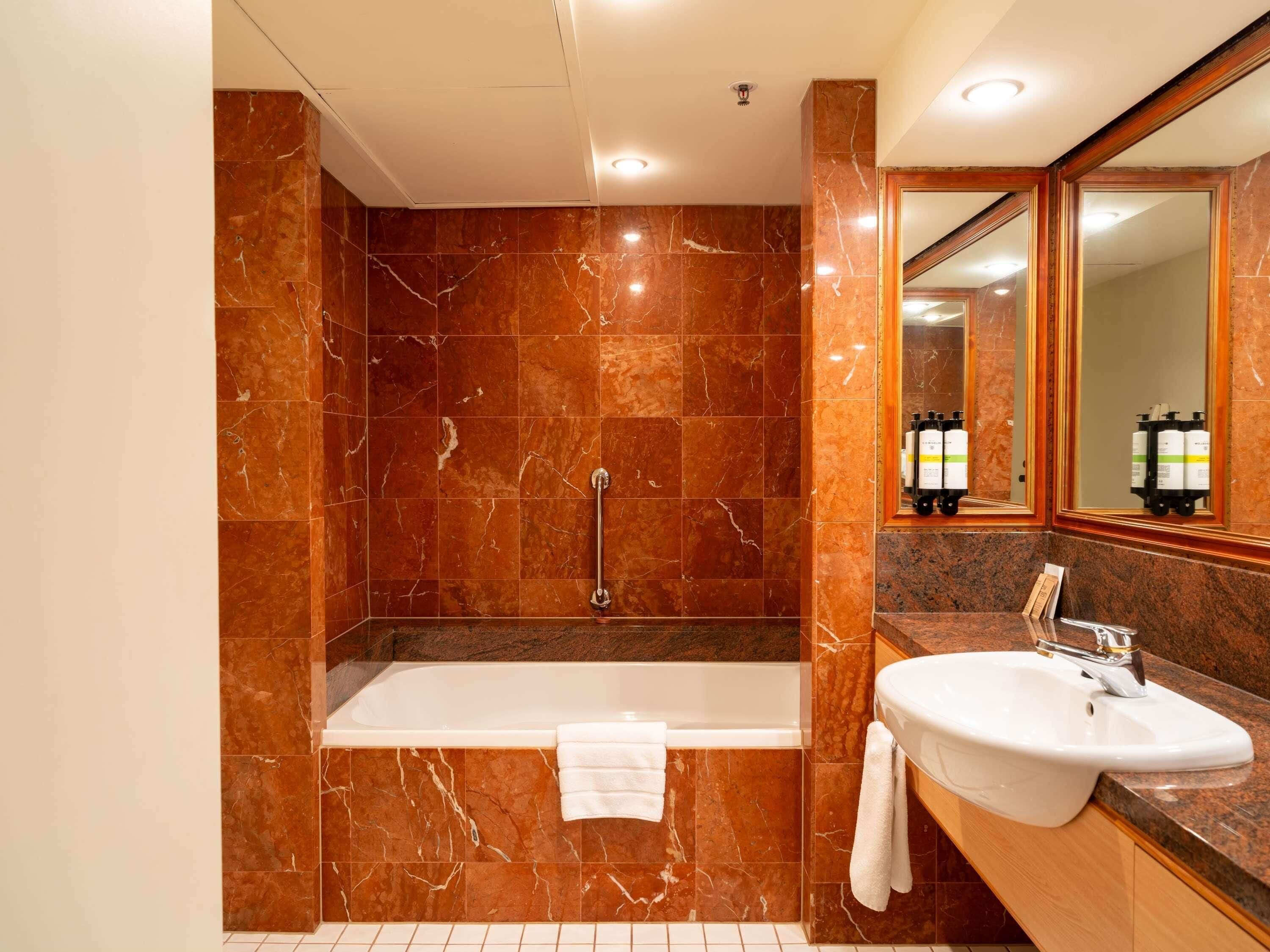 A bathroom with a bathtub, a sink, and a mirror.