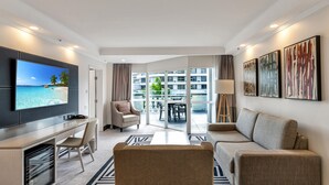 Una camera d'albergo moderna con TV, scrivania, divano e un balcone vista città.