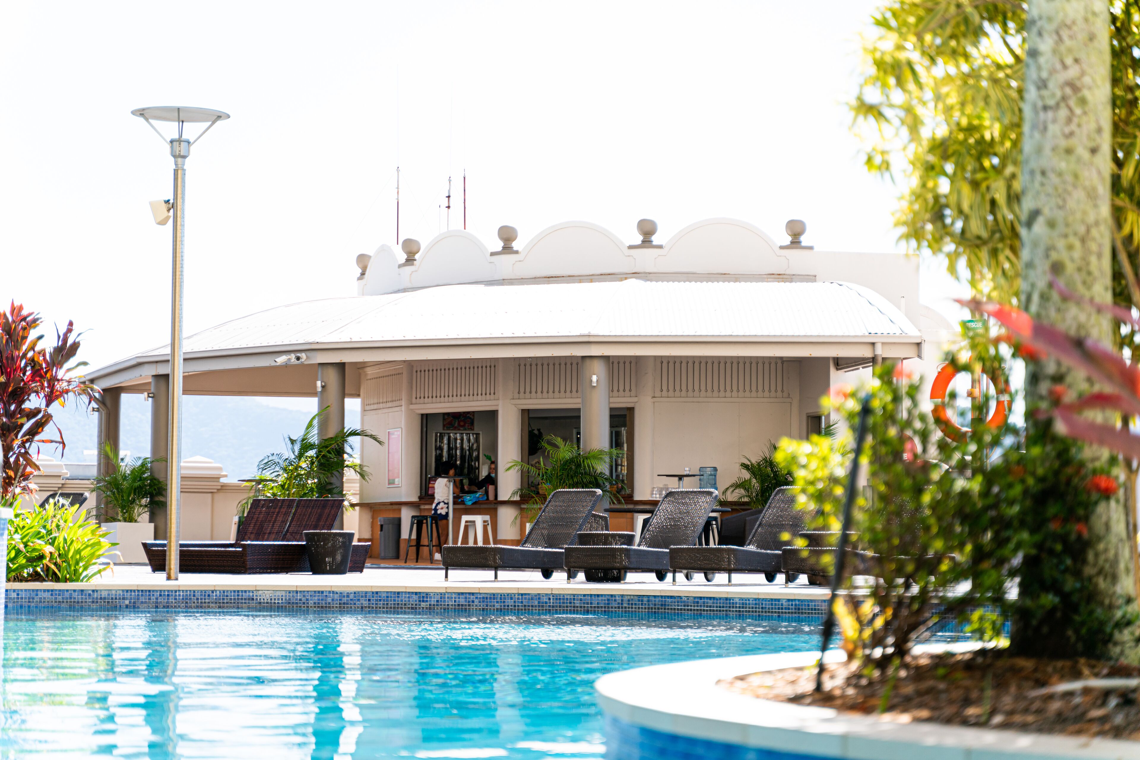 A pool area with lounge chairs and a covered seating area.