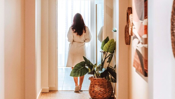 A hallway with a large potted plant, a door, and a wall with framed pictures. - Pullman Cairns International (Cairns)