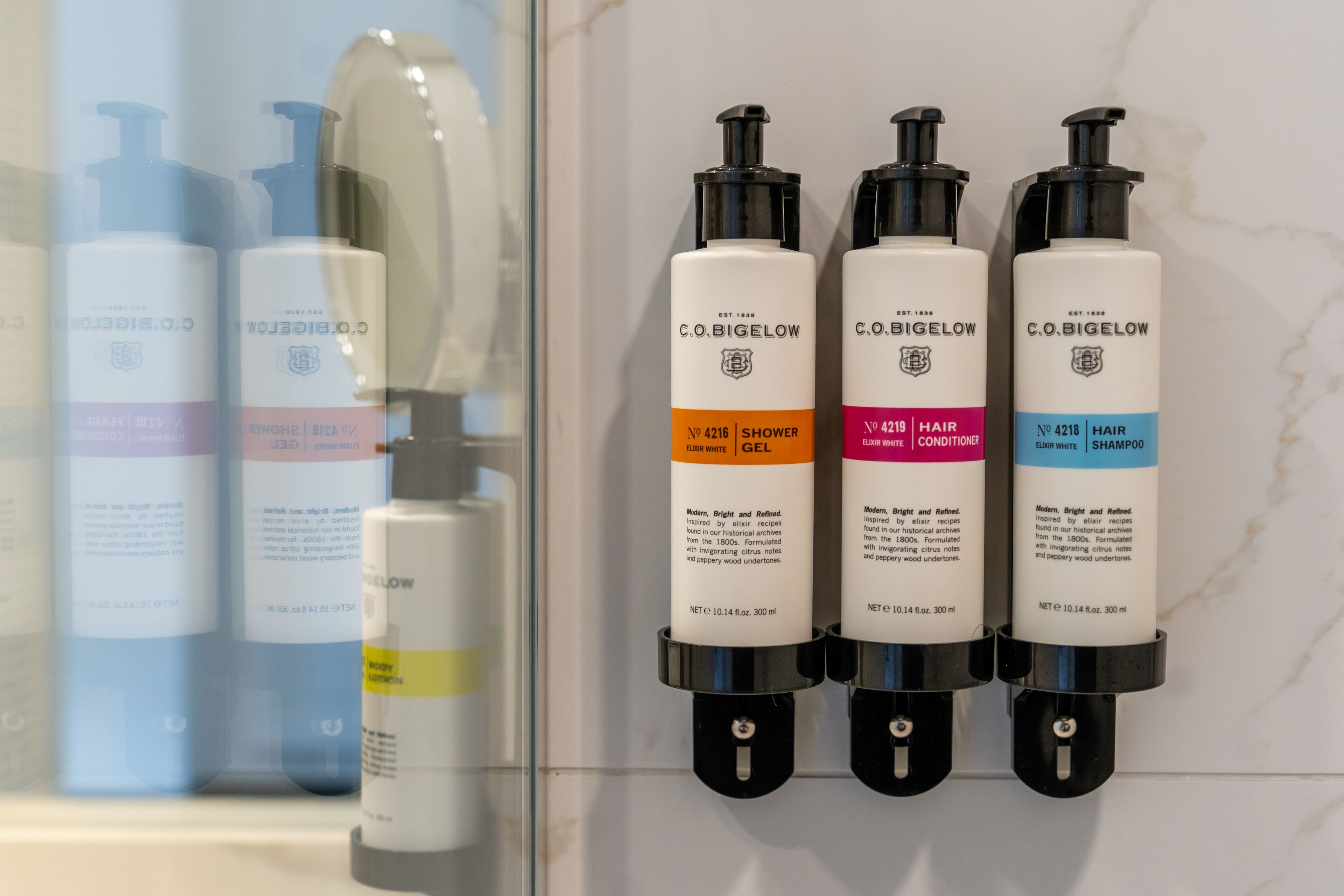 Un baño con cuatro botellas de productos C.O. Bigelow: gel de ducha, acondicionador para el cabello y champú.