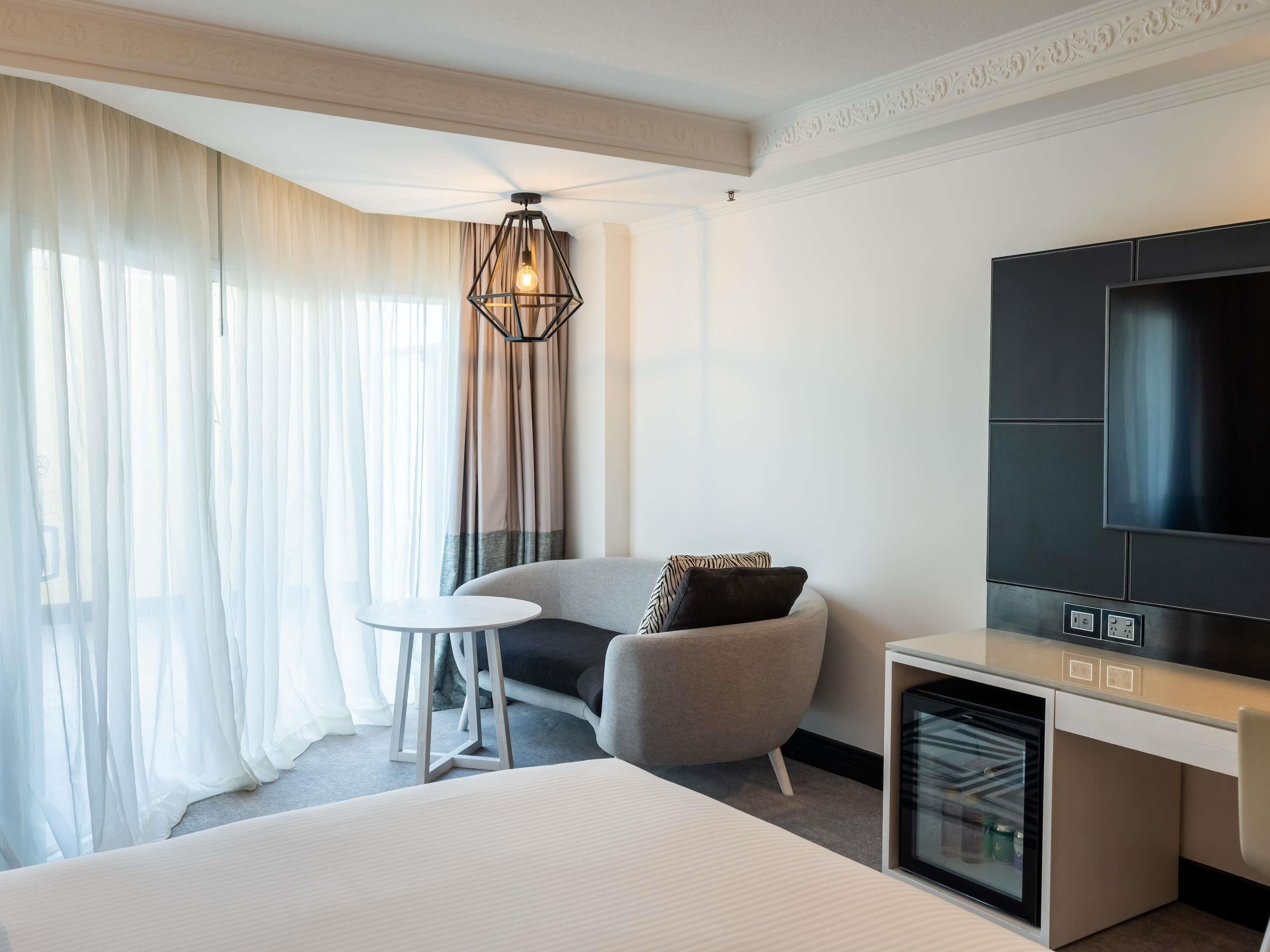 Une chambre d’hôtel équipée d’un lit, d’une petite table, d’une chaise, d’une télévision et d’un mini-bar.