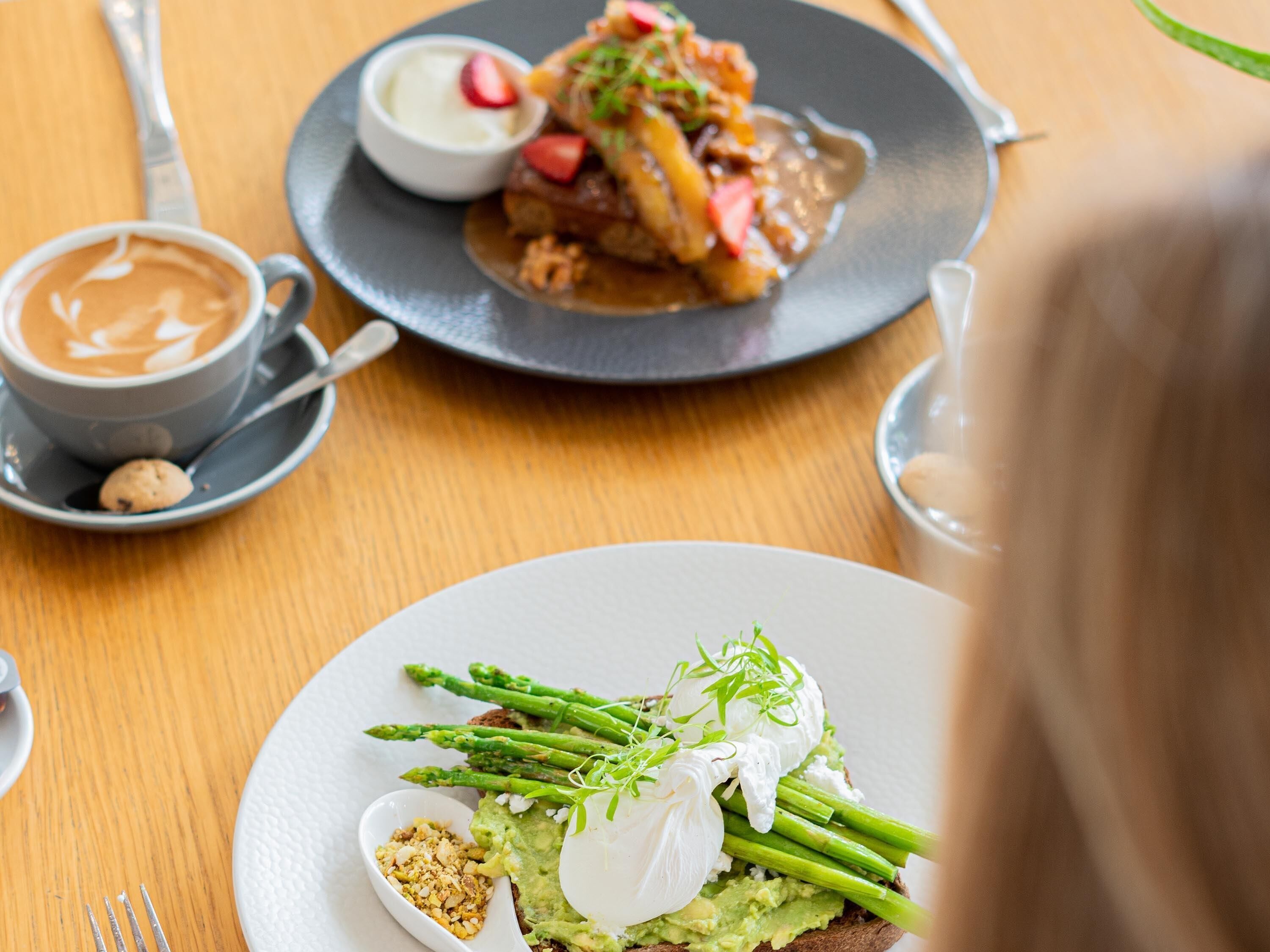 Een eettafel met eten, een kop koffie en een vork.
